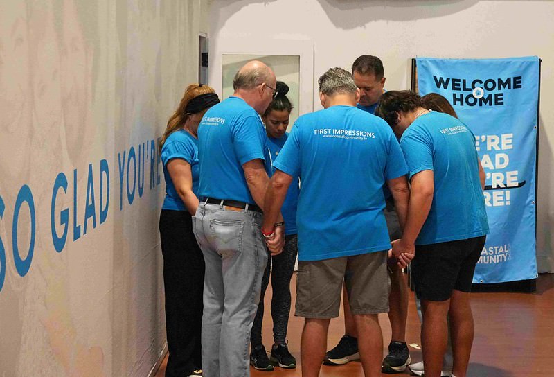54851924023_7454507872_c Two men in blue shits smiling and talking in Parkland, Coastal Community Church serve team